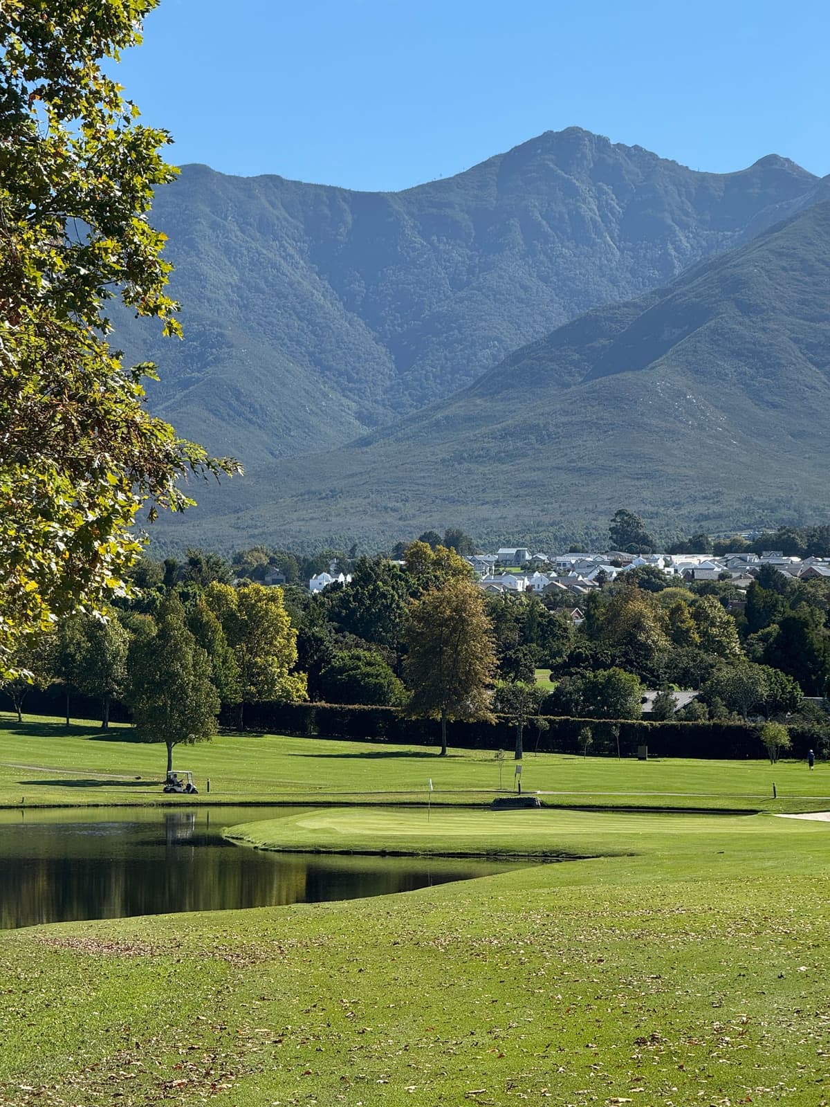 A green golf course set below dramatic coastal hills